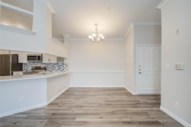 2111 Welch St Unit A321, Houston, TX 77019 - kitchen with appliances with stainless steel finishes, a chandelier, a sink, light countertops, and a peninsula