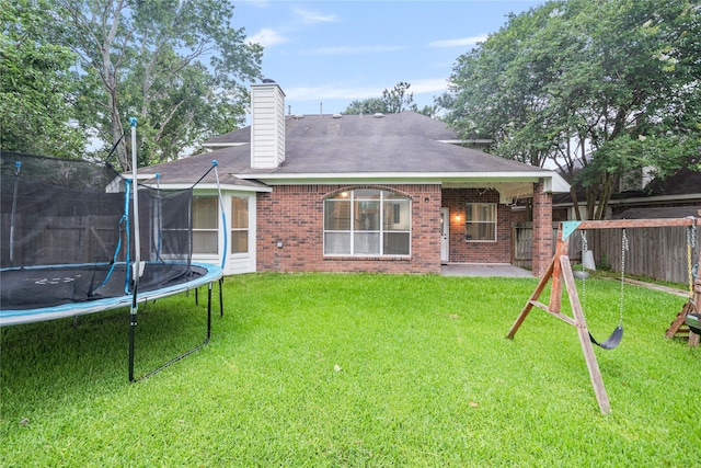 19315 Oak Station Dr, Humble, TX 77346 - back of property with a trampoline, brick siding, a chimney, and a patio area