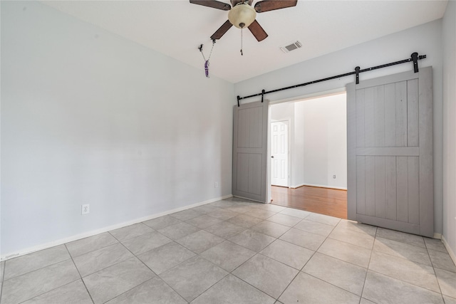19315 Oak Station Dr, Humble, TX 77346 - spare room featuring a barn door, light tile patterned floors, ceiling fan, and baseboards