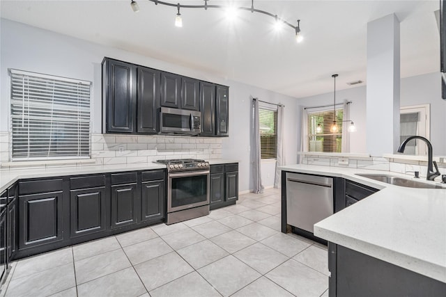 19315 Oak Station Dr, Humble, TX 77346 - kitchen featuring stainless steel appliances, a sink, dark cabinetry, tasteful backsplash, and light tile patterned flooring