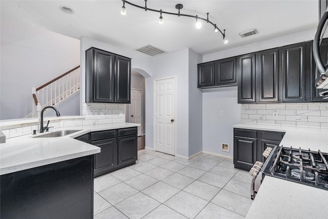 19315 Oak Station Dr, Humble, TX 77346 - kitchen featuring a sink, tasteful backsplash, range with gas cooktop, arched walkways, and dark cabinets