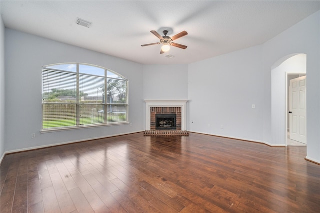 19315 Oak Station Dr, Humble, TX 77346 - unfurnished living room with a ceiling fan, arched walkways, hardwood / wood-style floors, and a brick fireplace