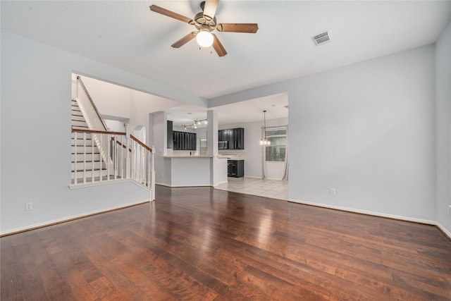 19315 Oak Station Dr, Humble, TX 77346 - unfurnished living room with light wood-style floors, stairway, a chandelier, ceiling fan, and baseboards