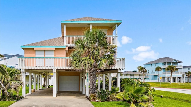 4122 Pirates Aly, Galveston, TX 77554 - coastal home featuring a carport, a garage, stucco siding, a balcony, and driveway