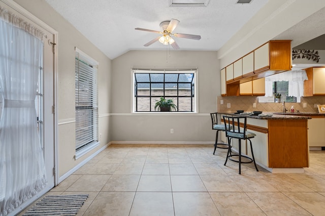 815 Millpond Dr, Sugar Land, TX 77498 - kitchen with dark countertops, backsplash, lofted ceiling, a kitchen bar, and a textured ceiling