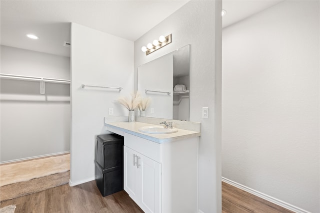 10530 Vinca Minor Ln, Houston, TX 77016 - bathroom with vanity, wood finished floors, baseboards, a walk in closet, and recessed lighting