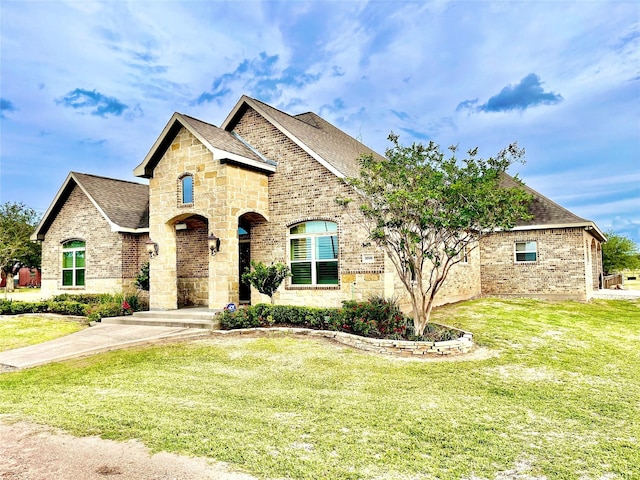 3898 County Road 135th Rd, Wharton, TX 77488 - french country style house featuring brick siding, a shingled roof, a front yard, and stone siding