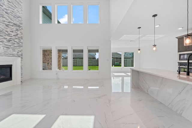 9818 Daffodil Springs Dr, Richmond, TX 77407 - unfurnished living room with light marble finish flooring, healthy amount of natural light, a large fireplace, a high ceiling, and recessed lighting