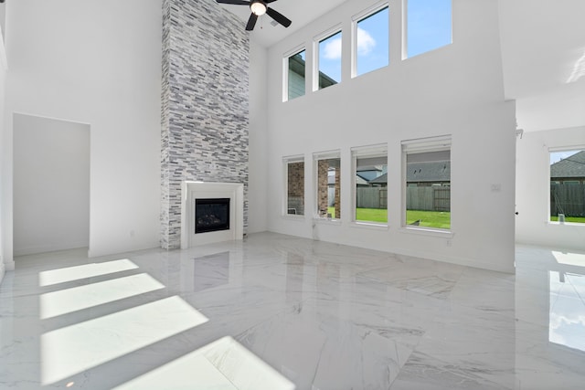 9818 Daffodil Springs Dr, Richmond, TX 77407 - unfurnished living room with a high ceiling, marble tiled floors, a ceiling fan, healthy amount of natural light, and a tiled fireplace