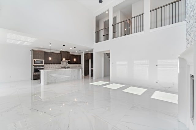 9818 Daffodil Springs Dr, Richmond, TX 77407 - unfurnished living room featuring light marble finish flooring, a sink, and a high ceiling