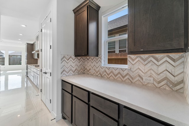 9818 Daffodil Springs Dr, Richmond, TX 77407 - kitchen featuring dark brown cabinets, plenty of natural light, decorative backsplash, and light countertops