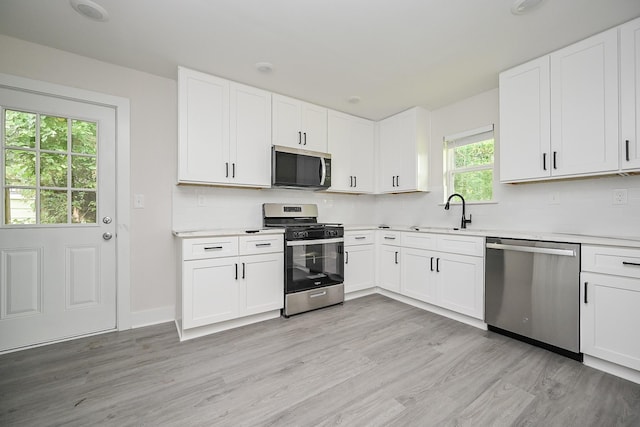 226 Hyta St, Houston, TX 77018 - kitchen featuring appliances with stainless steel finishes, a sink, backsplash, light countertops, and light wood finished floors