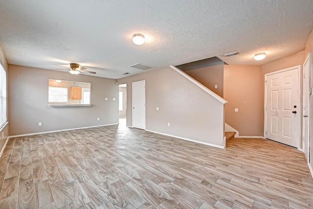 1406 Hade Falls Ln, Houston, TX 77073 - unfurnished living room with light wood-type flooring, ceiling fan, stairway, a textured ceiling, and baseboards