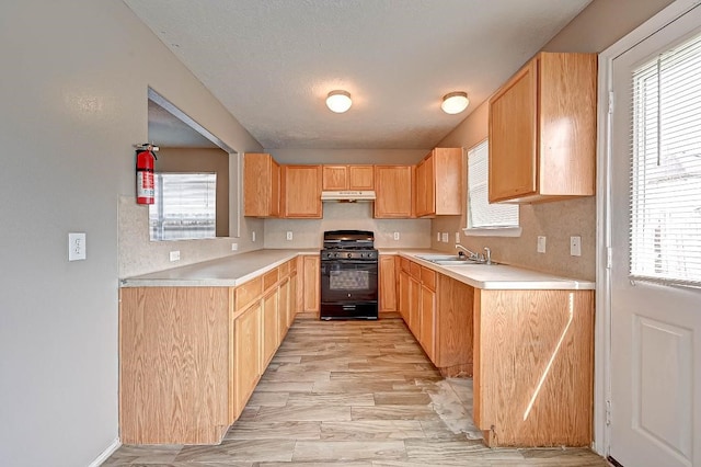 1406 Hade Falls Ln, Houston, TX 77073 - kitchen featuring black gas stove, under cabinet range hood, light countertops, a sink, and tasteful backsplash