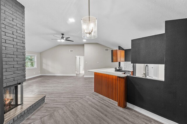 16026 Beechnut St, Houston, TX 77083 - kitchen featuring a ceiling fan, a brick fireplace, stainless steel stove, vaulted ceiling, and light wood-type flooring