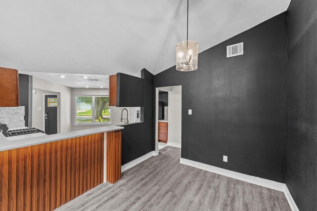 16026 Beechnut St, Houston, TX 77083 - kitchen featuring wood finished floors, light countertops, brown cabinets, and hanging light fixtures
