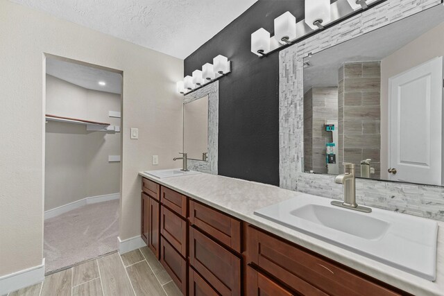 16026 Beechnut St, Houston, TX 77083 - full bath featuring double vanity, wood finished floors, a textured ceiling, and a tile shower