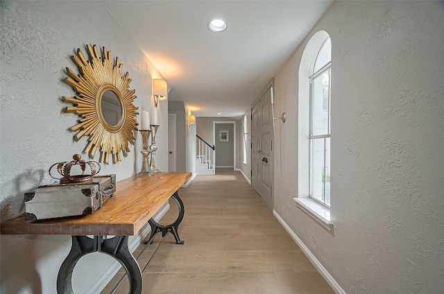 13622 Indian Creek Rd, Houston, TX 77079 - hallway with light wood finished floors, a textured wall, stairway, recessed lighting, and baseboards