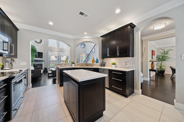6218 Southcott Ct, Katy, TX 77450 - kitchen with stainless steel appliances, light countertops, light tile patterned flooring, a sink, and crown molding