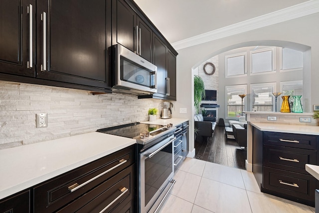 6218 Southcott Ct, Katy, TX 77450 - kitchen featuring stainless steel appliances, ornamental molding, a warm lit fireplace, light countertops, and backsplash