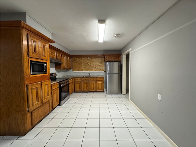 10509 Kelburn Dr, Houston, TX 77016 - kitchen with appliances with stainless steel finishes, under cabinet range hood, a sink, brown cabinetry, and light tile patterned floors