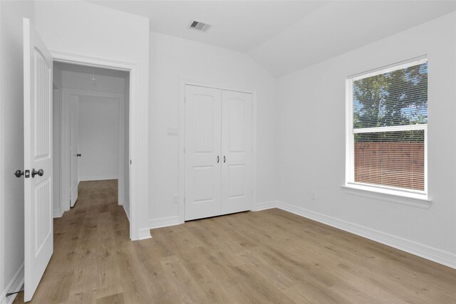 0 Basswood St, Houston, TX 77022 - unfurnished bedroom with light wood-style floors, lofted ceiling, a closet, and baseboards