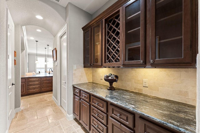 74 Spincaster Dr, Spring, TX 77389 - bar area featuring stone tile flooring, decorative backsplash, recessed lighting, arched walkways, and hanging light fixtures