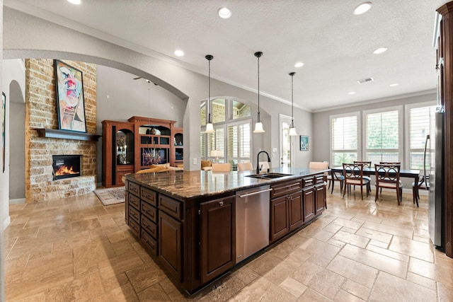 74 Spincaster Dr, Spring, TX 77389 - kitchen with stainless steel appliances, stone tile flooring, crown molding, dark brown cabinets, and a center island with sink