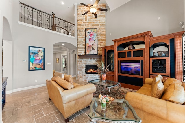 74 Spincaster Dr, Spring, TX 77389 - living room featuring high vaulted ceiling, arched walkways, a fireplace, ceiling fan, and stone tile floors