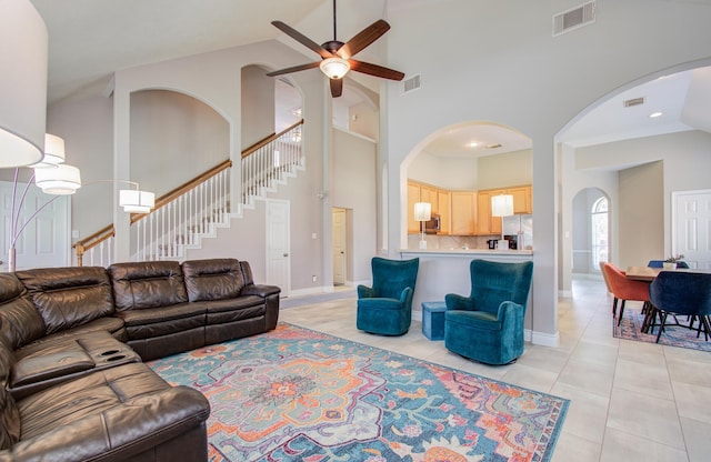 12807 Sienna Trails Dr, Tomball, TX 77377 - living room featuring arched walkways, ceiling fan, high vaulted ceiling, stairs, and light tile patterned flooring