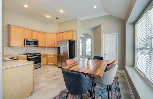 12807 Sienna Trails Dr, Tomball, TX 77377 - kitchen with appliances with stainless steel finishes, light brown cabinets, arched walkways, decorative backsplash, and light countertops