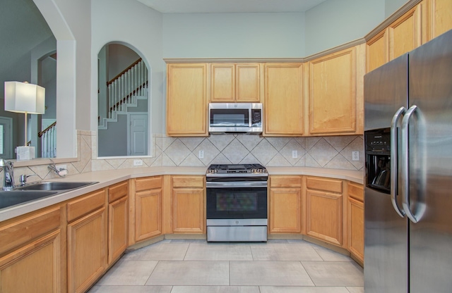 12807 Sienna Trails Dr, Tomball, TX 77377 - kitchen featuring appliances with stainless steel finishes, light countertops, tasteful backsplash, light tile patterned floors, and a sink