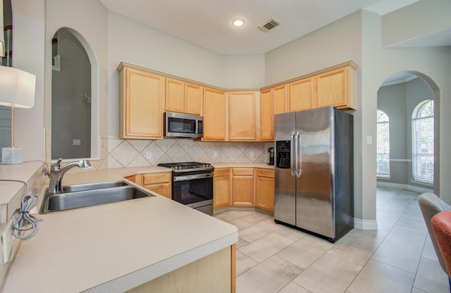 12807 Sienna Trails Dr, Tomball, TX 77377 - kitchen with appliances with stainless steel finishes, light brown cabinetry, arched walkways, a sink, and recessed lighting