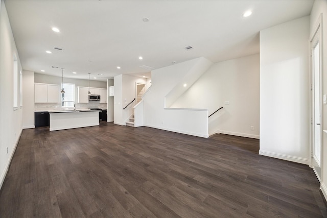 1805 Mills St, Houston, TX 77026 - unfurnished living room featuring recessed lighting, dark wood-type flooring, baseboards, a sink, and stairway