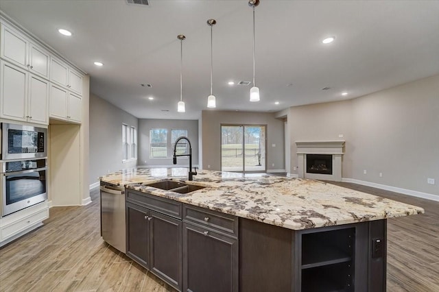 7563 Congress Trail Way, Porter, TX 77365 - kitchen with appliances with stainless steel finishes, a sink, light wood-style flooring, light stone counters, and recessed lighting