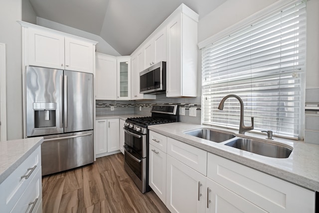 146 S Star Ridge Cir, The Woodlands, TX 77382 - kitchen featuring stainless steel appliances, a sink, lofted ceiling, white cabinetry, and glass insert cabinets