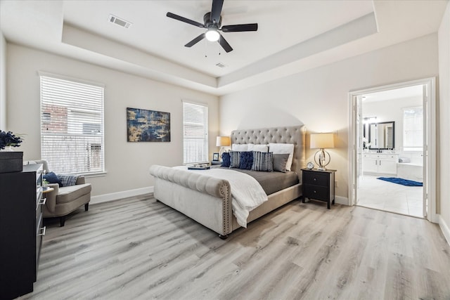 13411 SE Via Chianti Ln, Cypress, TX 77429 - bedroom featuring a raised ceiling, baseboards, wood finished floors, and connected bathroom