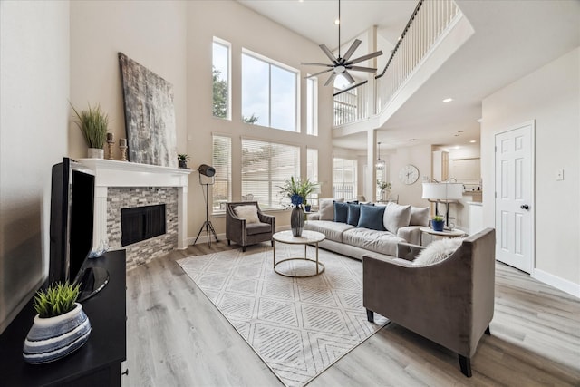 13411 SE Via Chianti Ln, Cypress, TX 77429 - living room with a stone fireplace, light wood-style flooring, a towering ceiling, and a ceiling fan