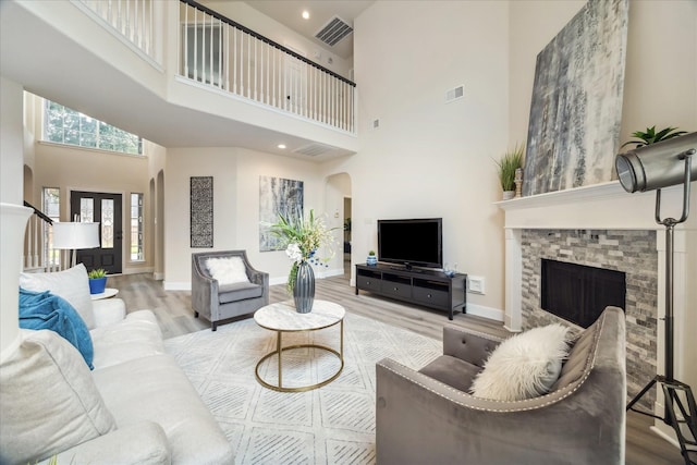 13411 SE Via Chianti Ln, Cypress, TX 77429 - living room with arched walkways, a towering ceiling, wood finished floors, a fireplace, and baseboards