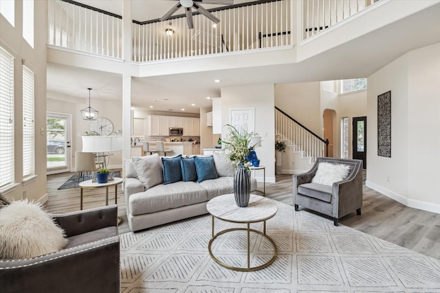 13411 SE Via Chianti Ln, Cypress, TX 77429 - living room featuring a high ceiling, arched walkways, a ceiling fan, baseboards, and light wood-type flooring