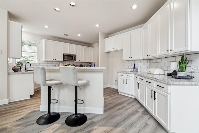 13411 SE Via Chianti Ln, Cypress, TX 77429 - kitchen with stainless steel microwave, tasteful backsplash, recessed lighting, white cabinetry, and a center island