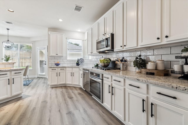 13411 SE Via Chianti Ln, Cypress, TX 77429 - kitchen with stainless steel appliances, white cabinetry, light wood finished floors, backsplash, and recessed lighting