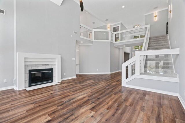 1806 Quiet Country Ct, Houston, TX 77345 - unfurnished living room featuring stairway, wood finished floors, baseboards, a towering ceiling, and a fireplace with flush hearth