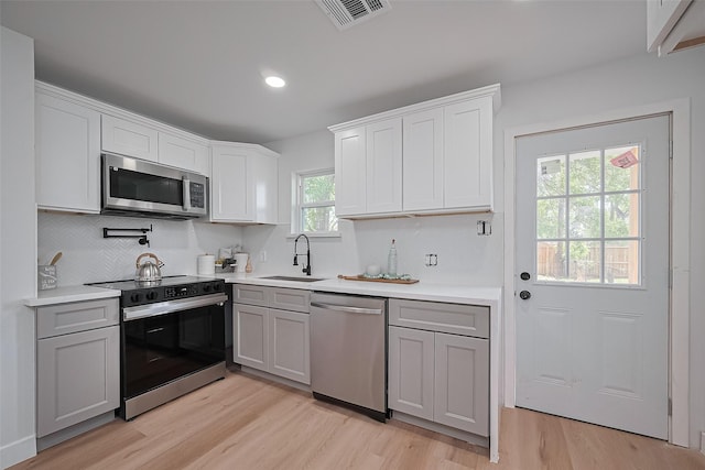 7406 Valeda Dr, Deer Park, TX 77536 - kitchen with stainless steel appliances, a sink, gray cabinets, light wood-style flooring, and tasteful backsplash