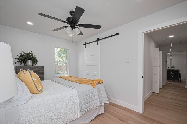 7406 Valeda Dr, Deer Park, TX 77536 - bedroom with light wood finished floors, a barn door, attic access, baseboards, and recessed lighting