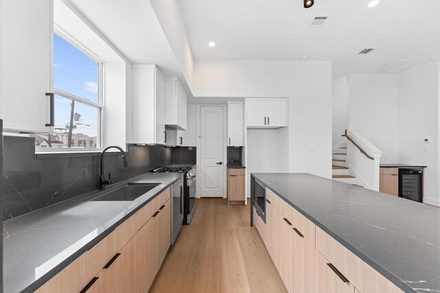 3209 Baer St Unit B, Houston, TX 77020 - kitchen featuring stainless steel appliances, beverage cooler, modern cabinets, light wood-style flooring, and light brown cabinets