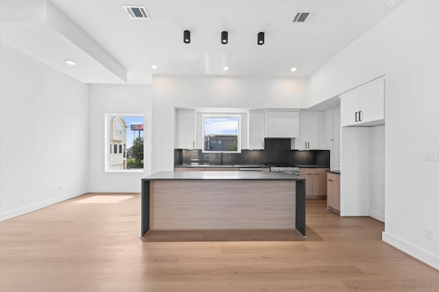 3209 Baer St Unit B, Houston, TX 77020 - kitchen with light wood finished floors, white cabinetry, dark countertops, tasteful backsplash, and recessed lighting