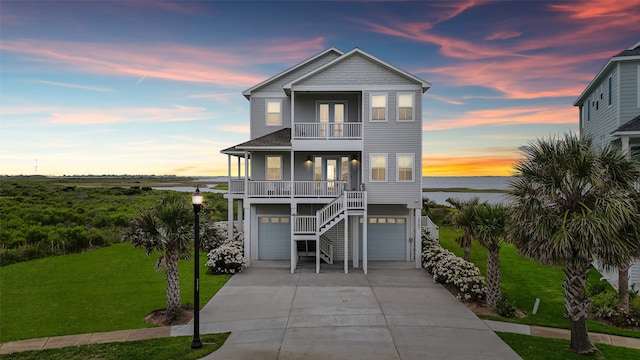 3903 Evening Primrose Dr, Galveston, TX 77554 - beach home featuring a balcony, a lawn, french doors, concrete driveway, and a garage
