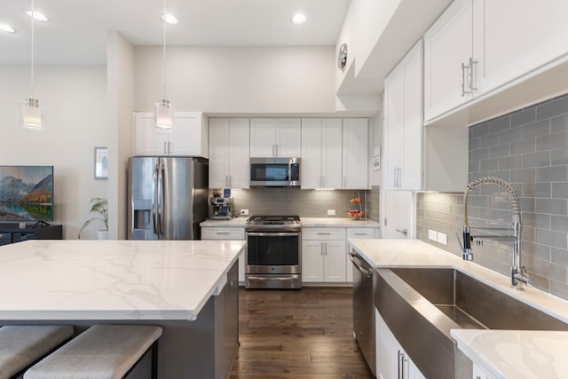 1703 Freeman St, Houston, TX 77009 - kitchen featuring stainless steel appliances, a sink, light stone counters, dark wood-style flooring, and backsplash