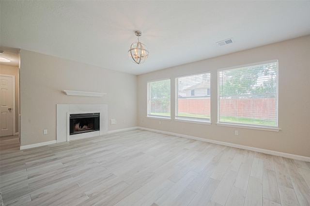 16502 N Glade Dr, Houston, TX 77073 - unfurnished living room with light wood-style flooring, baseboards, a fireplace, and a chandelier